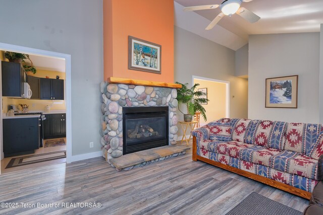 2697 Rendezvous Dr, Driggs, ID 83422 - living room featuring high vaulted ceiling, wood finished floors, a stone fireplace, a ceiling fan, and baseboards