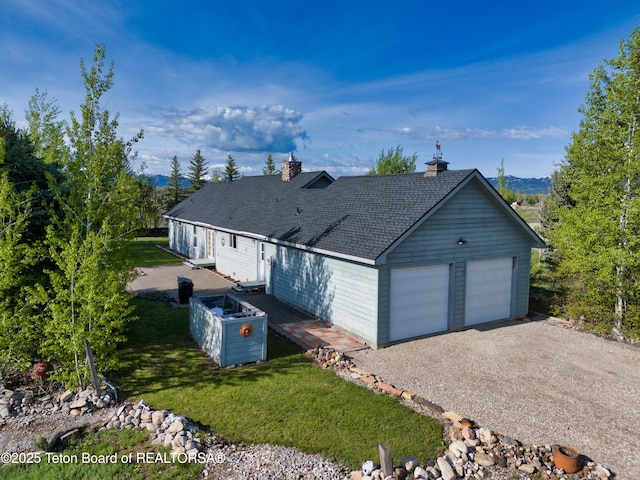 2697 Rendezvous Dr, Driggs, ID 83422 - ranch-style home featuring a shingled roof, a detached garage, a front lawn, and a mountain view