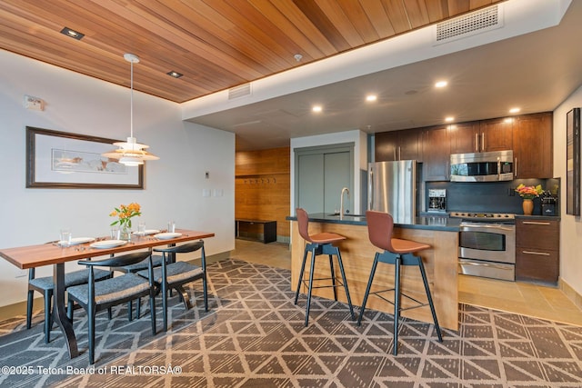 3335 W Villlage Dr Unit 201/203, Teton Village, WY 83025 - kitchen with stainless steel appliances, dark countertops, a sink, recessed lighting, and a breakfast bar