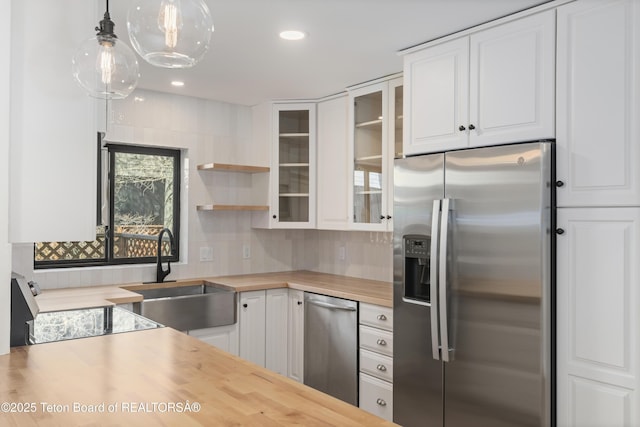 826 Powderhorn Ln Unit C, Jackson, WY 83001 - kitchen with stainless steel appliances, a sink, butcher block counters, white cabinetry, and glass insert cabinets