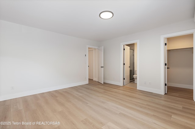 826 Powderhorn Ln Unit C, Jackson, WY 83001 - unfurnished bedroom featuring light wood-type flooring, baseboards, a walk in closet, ensuite bathroom, and a closet
