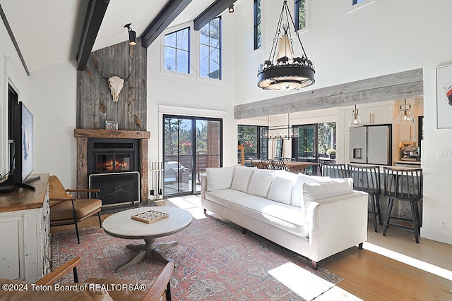 living room featuring high vaulted ceiling, beamed ceiling, wood finished floors, healthy amount of natural light, and a large fireplace