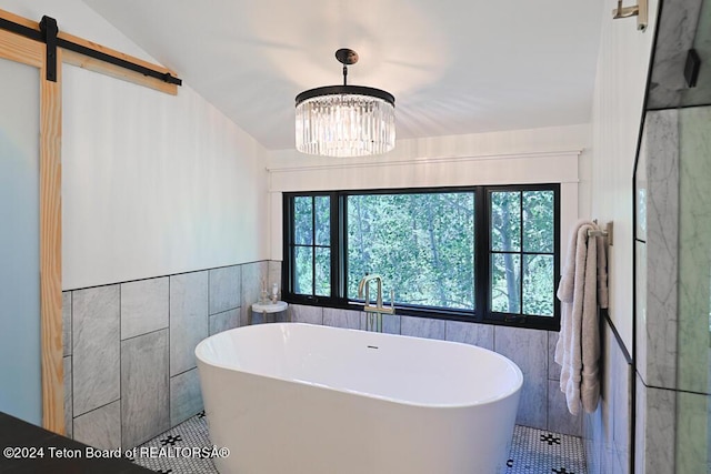 full bath with tile patterned floors, tile walls, a soaking tub, and a chandelier