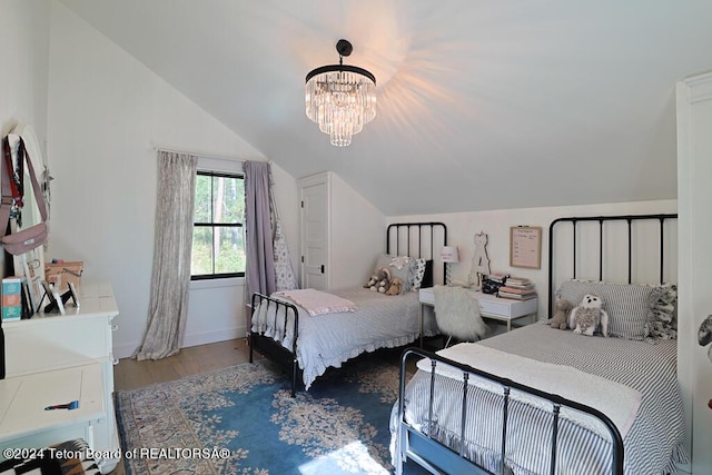 bedroom with lofted ceiling, wood finished floors, and a chandelier