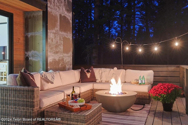 deck at night featuring an outdoor living space with a fire pit