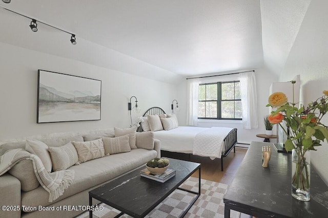 bedroom with lofted ceiling, wood finished floors, and baseboard heating