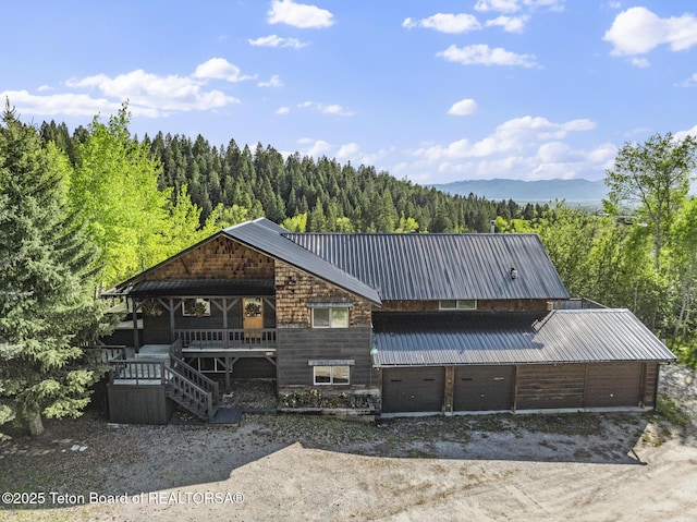 2077 Highland Way, Victor, ID 83455 - chalet / cabin featuring a view of trees, dirt driveway, a metal roof, and a porch