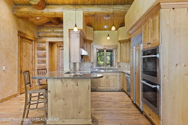 5725 W Caddis Fly Dr, Wilson, WY 83014 - kitchen featuring rustic walls, light wood-style flooring, a kitchen bar, stainless steel appliances, and a wood ceiling with exposed beams