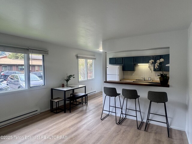 385 N Glenwood St, Jackson, WY 83001 - kitchen featuring freestanding refrigerator, a breakfast bar, a sink, dark countertops, and baseboard heating