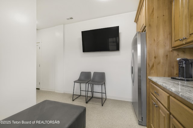 2399 Chapel Rd, Swan Valley, ID 83449 - kitchen featuring freestanding refrigerator, brown cabinets, baseboards, and light stone countertops