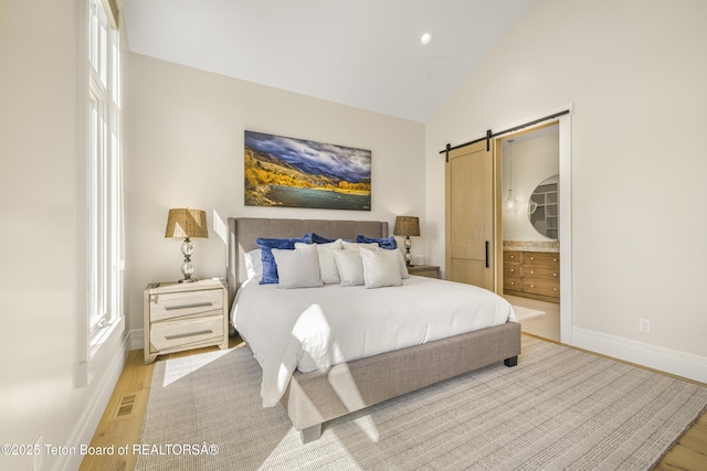 2399 Chapel Rd, Swan Valley, ID 83449 - bedroom with a barn door, light wood finished floors, baseboards, vaulted ceiling, and recessed lighting