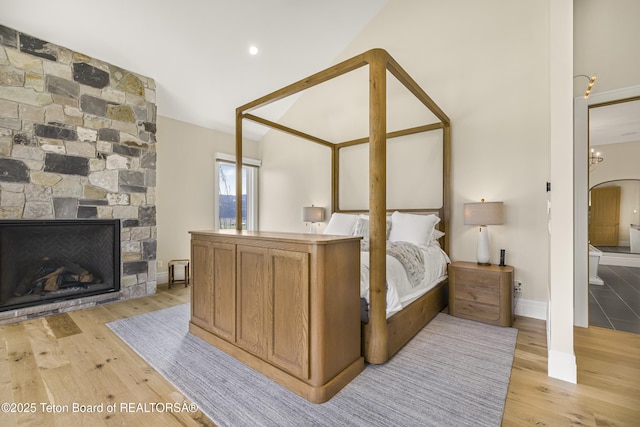 2399 Chapel Rd, Swan Valley, ID 83449 - bedroom with light wood finished floors, vaulted ceiling, a stone fireplace, baseboards, and arched walkways