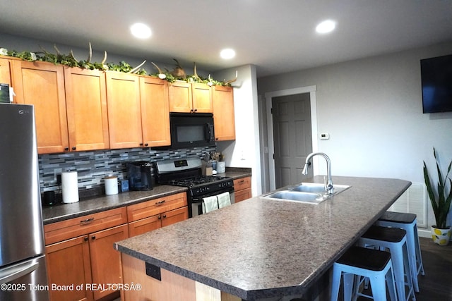 418 Par Ave, Pinedale, WY 82941 - kitchen with stainless steel appliances, a sink, a kitchen island with sink, decorative backsplash, and a breakfast bar area
