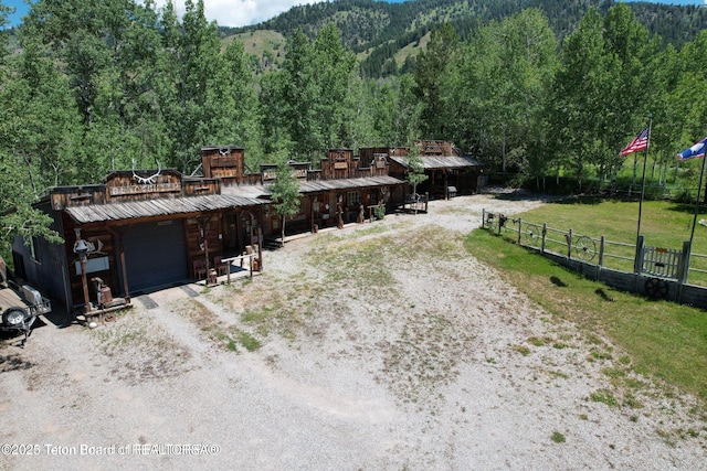 216 County Road 179s, Thayne, WY 83127 - view of front of house with an outbuilding, an attached garage, a view of trees, an exterior structure, and dirt driveway
