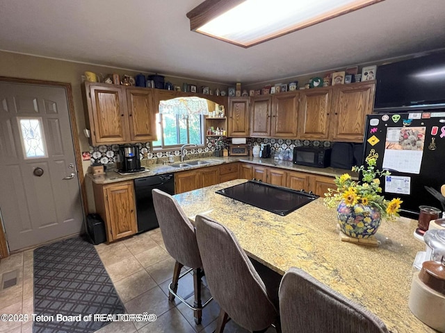 216 County Road 179s, Thayne, WY 83127 - kitchen with black appliances, a sink, brown cabinets, and a breakfast bar
