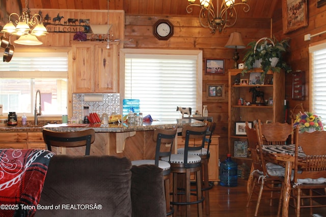 588 S Oak St, Labarge, WY 83123 - kitchen featuring a chandelier, wood walls, wood finished floors, wooden ceiling, and a breakfast bar area