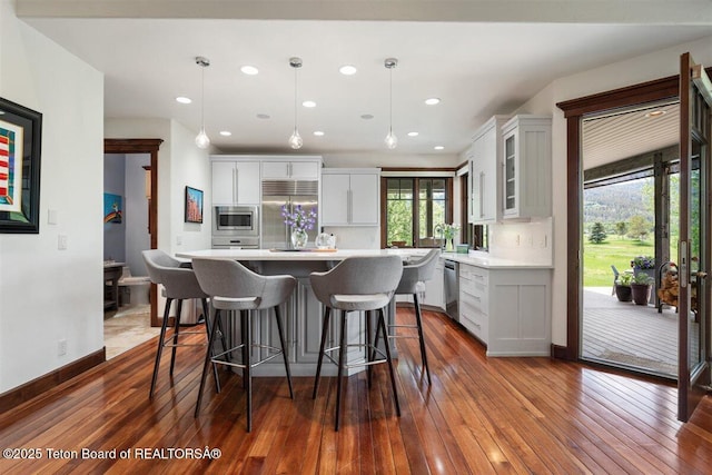 62 Hastings Dr, Victor, ID 83455 - kitchen with built in appliances, light countertops, dark wood-style flooring, glass insert cabinets, and a breakfast bar