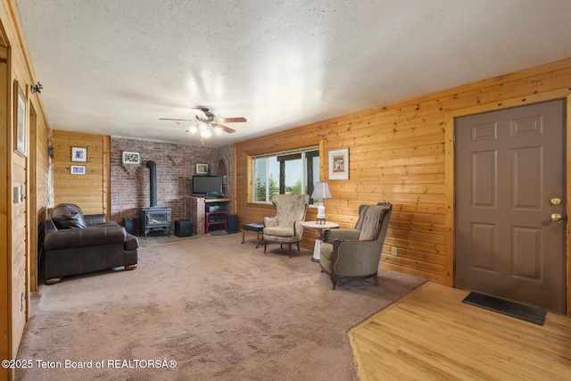 188 E 3000 S, Driggs, ID 83422 - carpeted living area featuring a wood stove, wood walls, a ceiling fan, and a textured ceiling