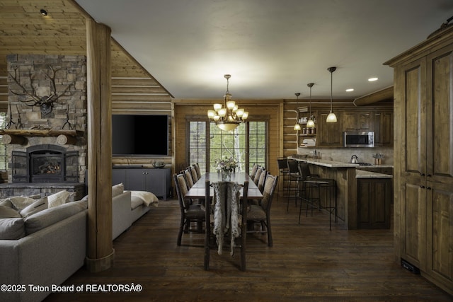 88 Blackfoot Trl, Victor, ID 83455 - dining room with dark wood-type flooring, rustic walls, a chandelier, a stone fireplace, and recessed lighting