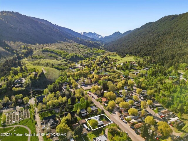755 Cache Creek Dr, Jackson, WY 83001 - aerial view of property and surrounding area with property boundaries highlighted, a heavily wooded area, and a mountainous background