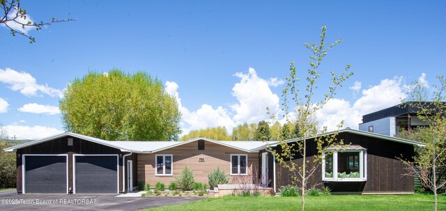 755 Cache Creek Dr, Jackson, WY 83001 - view of front facade featuring an attached garage, asphalt driveway, metal roof, and a front lawn