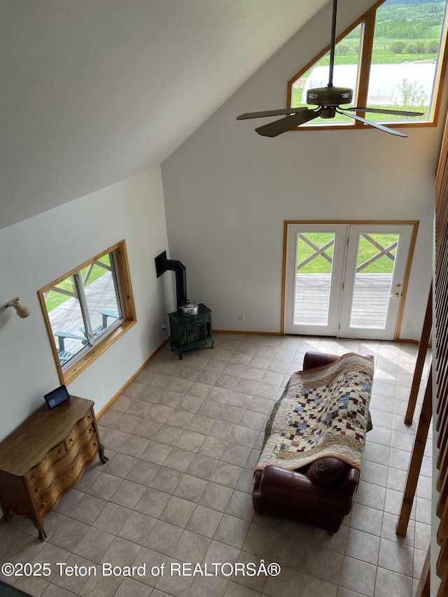 522 El Clark Ln, Smoot, WY 83126 - living area with high vaulted ceiling, a wood stove, a ceiling fan, and light tile patterned flooring