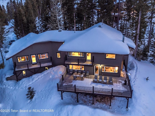 6960 Lupine Trl, Wilson, WY 83001 - snow covered house featuring an outdoor living space, a forest view, and a deck