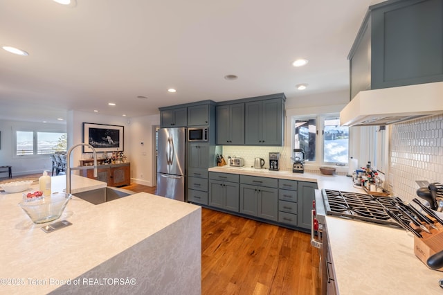 6960 Lupine Trl, Wilson, WY 83001 - kitchen with appliances with stainless steel finishes, wood finished floors, backsplash, light countertops, and a sink
