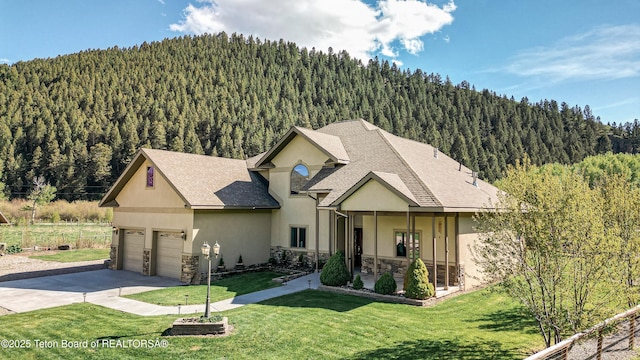 33 Wagon Rut Ln, Auburn, WY 83111 - view of front of home with a view of trees, stone siding, stucco siding, and concrete driveway