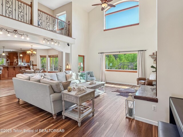 33 Wagon Rut Ln, Auburn, WY 83111 - living area featuring baseboards, wood finished floors, ceiling fan, a towering ceiling, and a chandelier