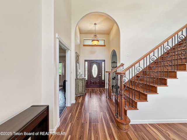 33 Wagon Rut Ln, Auburn, WY 83111 - foyer featuring arched walkways, a towering ceiling, wood finished floors, baseboards, and stairs