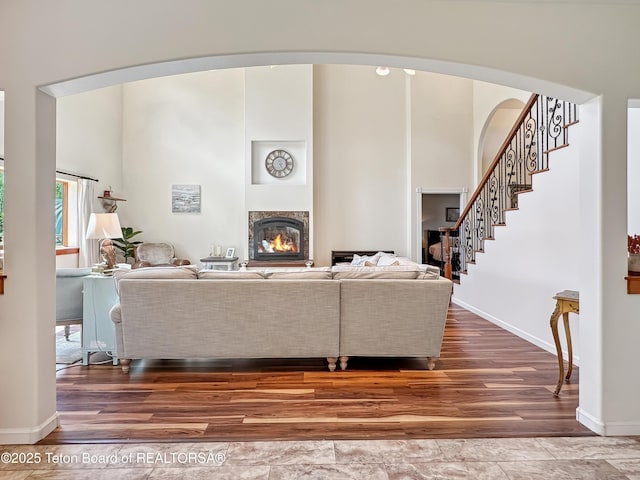 33 Wagon Rut Ln, Auburn, WY 83111 - living area featuring arched walkways, wood finished floors, a glass covered fireplace, stairs, and baseboards