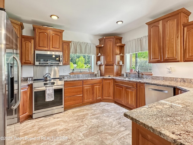 33 Wagon Rut Ln, Auburn, WY 83111 - kitchen with stainless steel appliances, open shelves, light stone countertops, a sink, and brown cabinetry