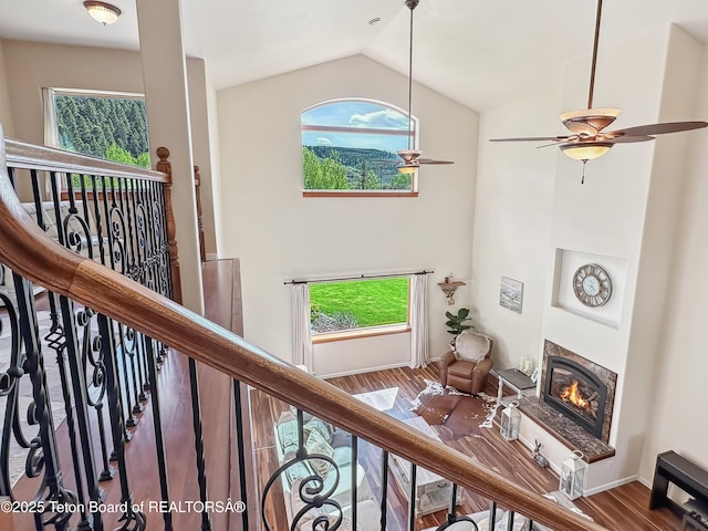 33 Wagon Rut Ln, Auburn, WY 83111 - staircase featuring a glass covered fireplace, wood finished floors, vaulted ceiling, plenty of natural light, and a ceiling fan