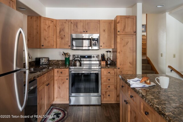 371 Snow King Loop, Jackson, WY 83001 - kitchen with appliances with stainless steel finishes, dark wood-style flooring, dark stone countertops, and a sink