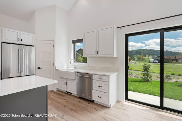 185 Columbine St, Alpine, WY 83128 - kitchen featuring appliances with stainless steel finishes, a sink, high vaulted ceiling, light countertops, and white cabinets