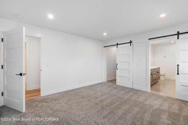185 Columbine St, Alpine, WY 83128 - unfurnished bedroom with a barn door, light carpet, recessed lighting, baseboards, and ensuite bath