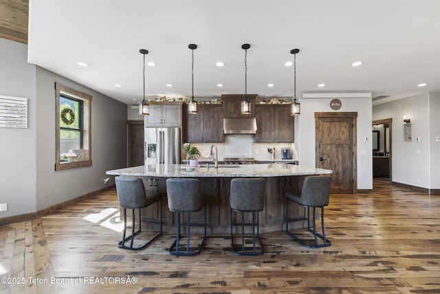 444 Riverview Dr, Alpine, WY 83128 - kitchen with stainless steel fridge with ice dispenser, under cabinet range hood, dark wood-style floors, baseboards, and recessed lighting