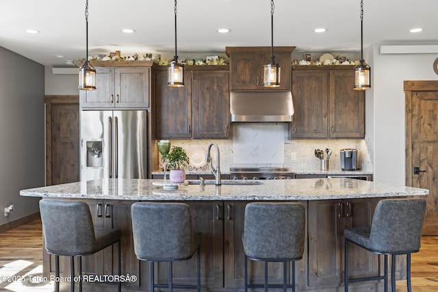 444 Riverview Dr, Alpine, WY 83128 - kitchen with stainless steel fridge, extractor fan, a sink, light wood finished floors, and decorative backsplash