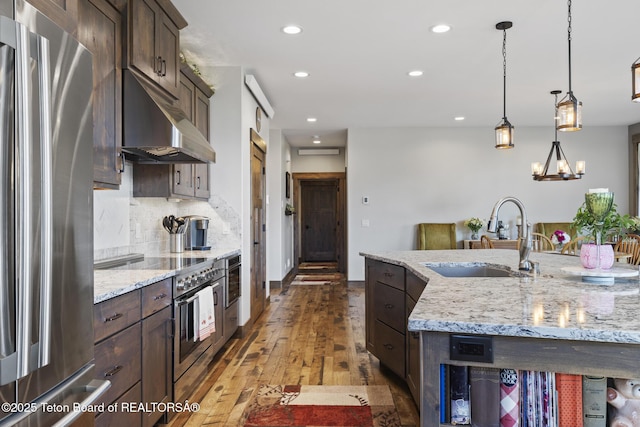 444 Riverview Dr, Alpine, WY 83128 - kitchen with stainless steel appliances, a sink, dark brown cabinetry, under cabinet range hood, and recessed lighting