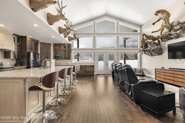 405 Vista Dr, Star Valley Ranch, WY 83127 - kitchen featuring appliances with stainless steel finishes, glass insert cabinets, high vaulted ceiling, a sink, and a breakfast bar area
