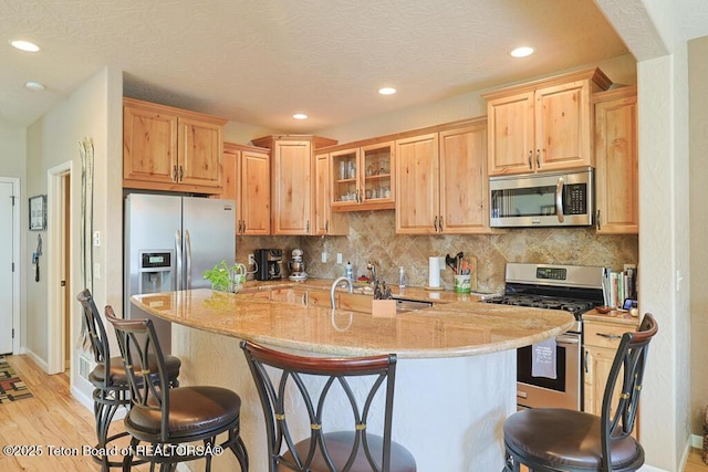 165 Cobble Creek Ln, Driggs, ID 83422 - kitchen featuring stainless steel appliances, a kitchen breakfast bar, light stone countertops, recessed lighting, and light wood-type flooring