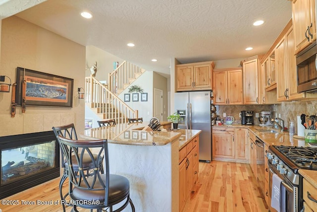165 Cobble Creek Ln, Driggs, ID 83422 - kitchen featuring stainless steel appliances, a sink, light wood-type flooring, recessed lighting, and light stone countertops