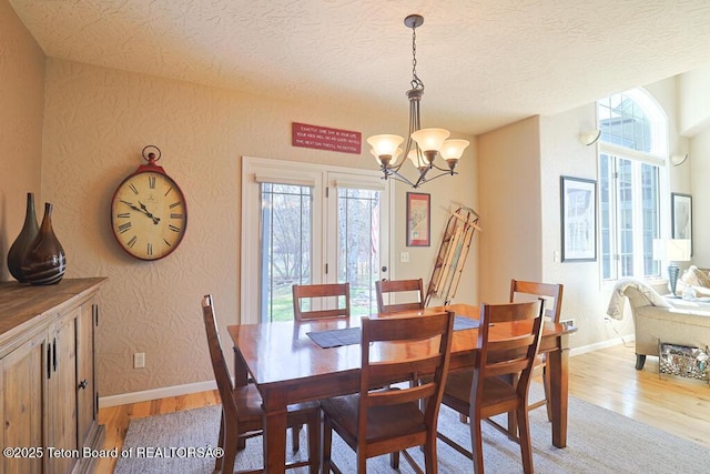 165 Cobble Creek Ln, Driggs, ID 83422 - dining area with light wood finished floors, a chandelier, baseboards, a textured wall, and a textured ceiling