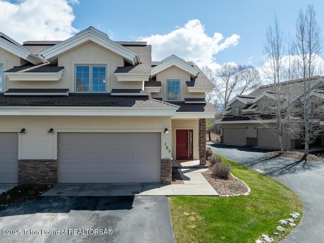 165 Cobble Creek Ln, Driggs, ID 83422 - view of front of property featuring stone siding, stucco siding, roof with shingles, an attached garage, and driveway