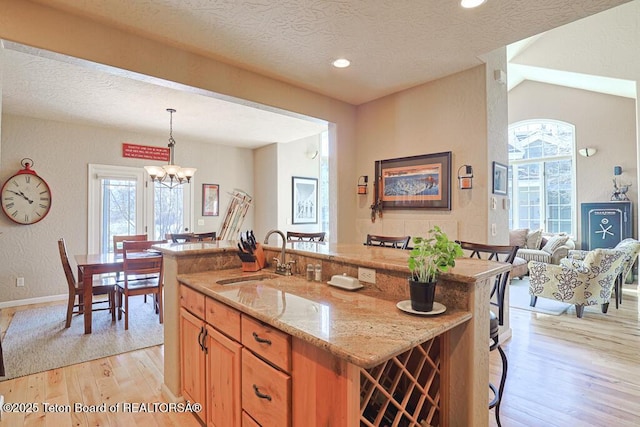 165 Cobble Creek Ln, Driggs, ID 83422 - kitchen featuring a sink, light wood finished floors, light stone counters, a textured ceiling, and pendant lighting