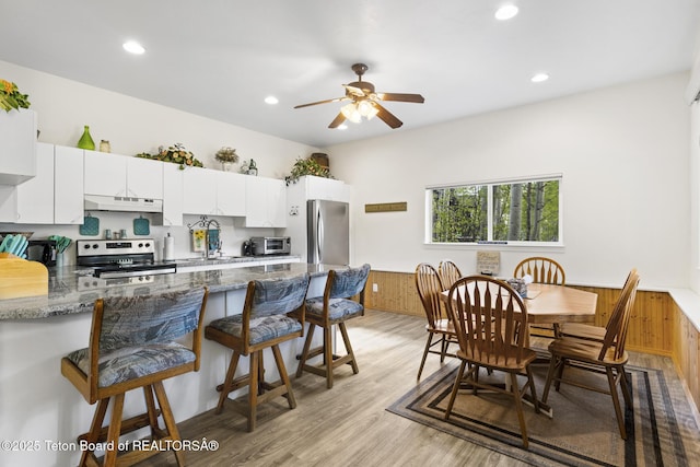 279 Vista E Dr, Star Valley Ranch, WY 83127 - kitchen with appliances with stainless steel finishes, under cabinet range hood, a peninsula, a breakfast bar, and recessed lighting