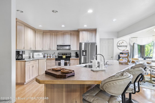 279 Vista E Dr, Star Valley Ranch, WY 83127 - kitchen featuring stainless steel appliances, under cabinet range hood, a sink, light brown cabinetry, and a breakfast bar area