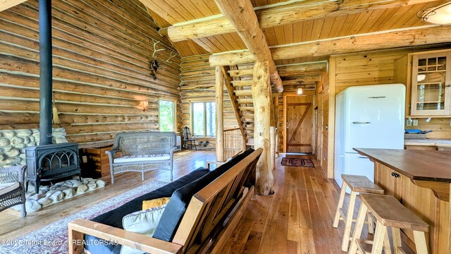 10559 Rammell Mountain Rd, Tetonia, ID 83452 - living room featuring wooden ceiling with exposed beams, rustic walls, a wood stove, and hardwood / wood-style floors