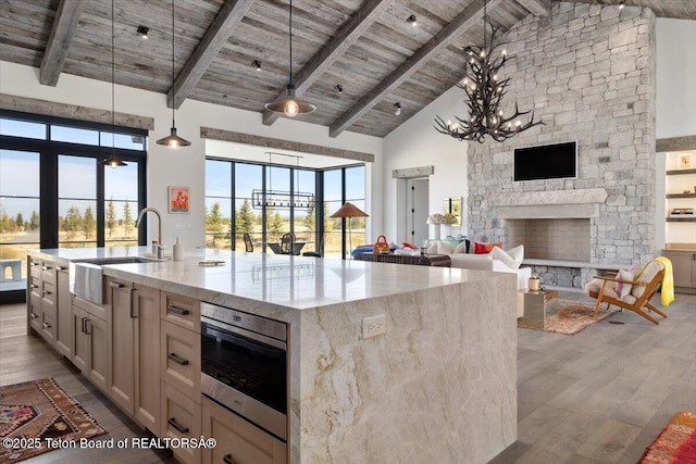 900 Mountain Bluebird Ct, Driggs, ID 83422 - kitchen featuring a sink, wooden ceiling with exposed beams, open floor plan, wood finished floors, and light stone counters